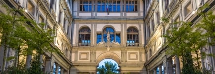 Among the intricate walls of an Italian building a marble statue sits above an archway.