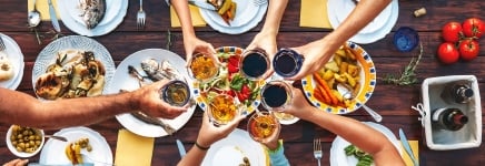 Hands clinking glasses on a table with food