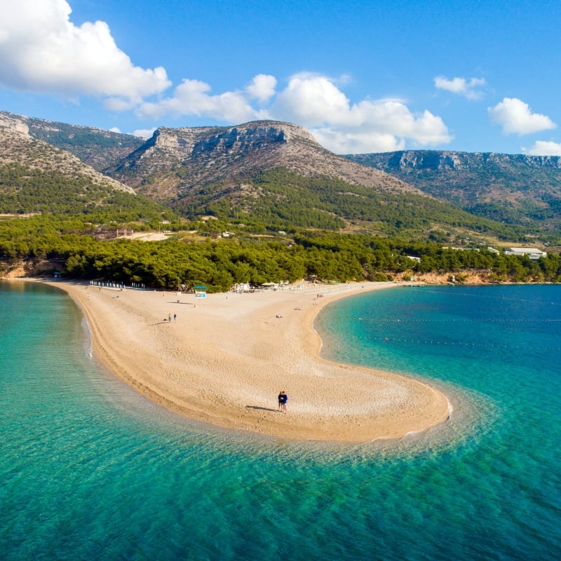 View of beach and blue waters on peninsula in Croatia with mountains in the background