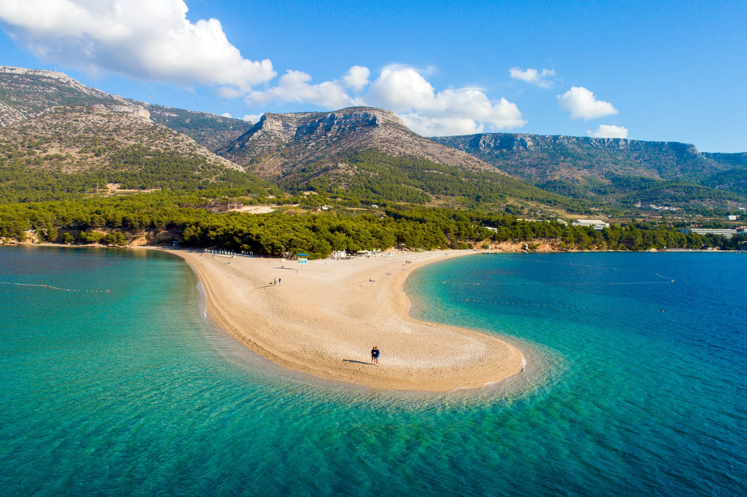 View of beach and blue waters on peninsula in Croatia with mountains in the background